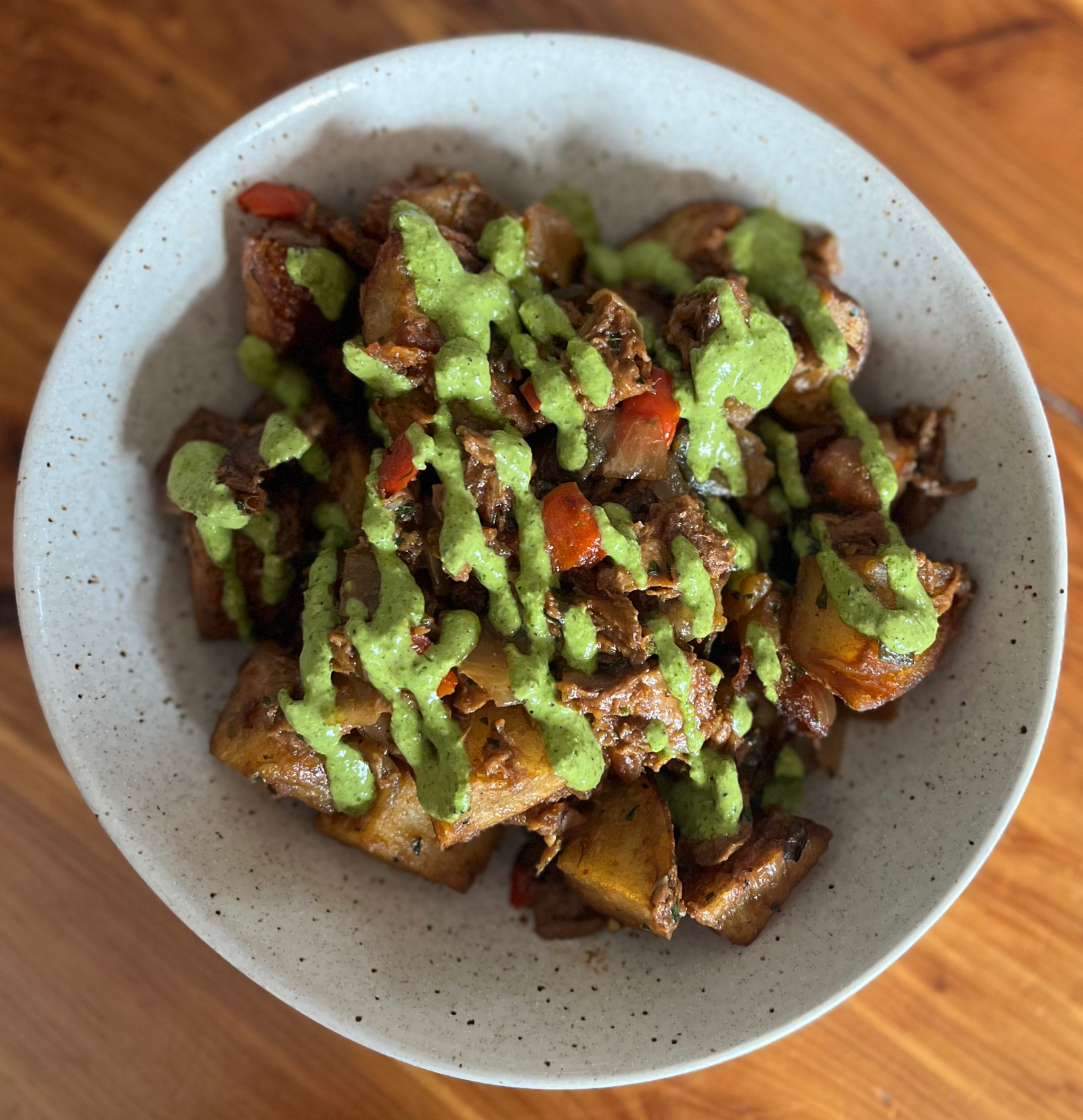 Retreat Gastro Pub: Speckled bowl filled with Harvest Shreds plant protein, breakfast potatoes, peppers, onions, veggie demi-glace and a drizzle of chimichurri. Vegan Hash.